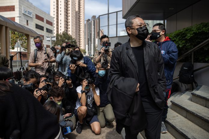 MORDAZA. El activista y profesor de derecho Benny Tai Yiu-ting (der.) se presenta ante la policía de Hong Kong, luego de ser incluido en la última lista de imputados por “conspiración de subversión”.
