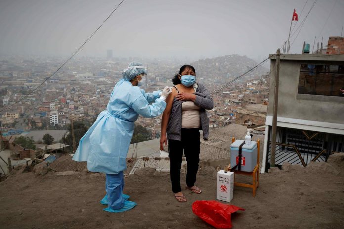 DOSIS. Una enfermera vacuna contra la Covid-19 a una pobladora de una barriada de Lima.