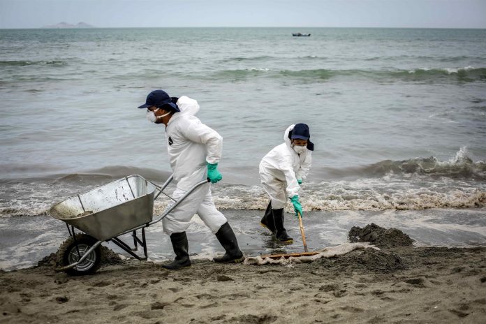 En la fotografía, trabajadores laboran en el retiro de petróleo de la arena de la playa de Ancón, en el norte de Lima.