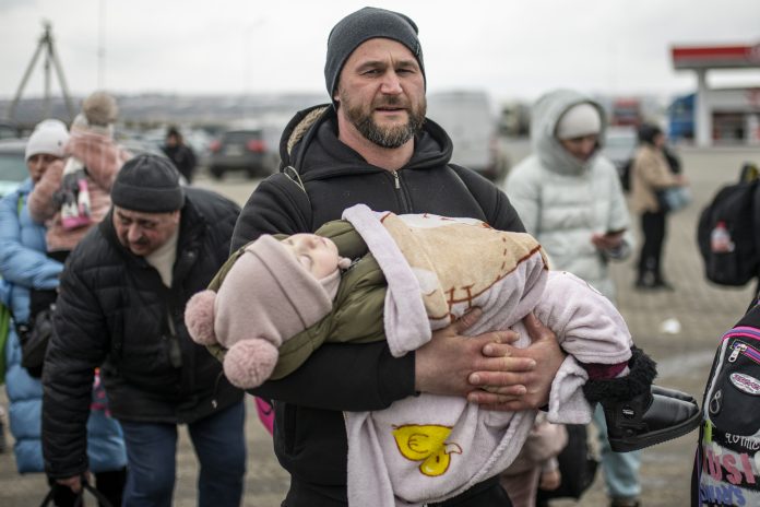 Un hombre con un niño en brazos en el paso fronterizo de Porubne, en el oeste de Ucrania.