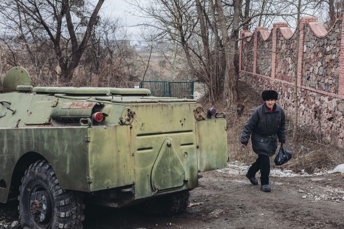 Un hombre camina junto a un vehículo blindado en Ucrania.